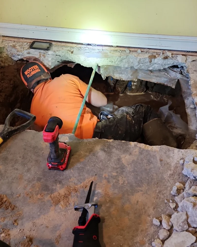 A professional technician inside an indoor concrete slab excavation locating a hidden water leak during an advanced plumbing Sapulpa leak detection job